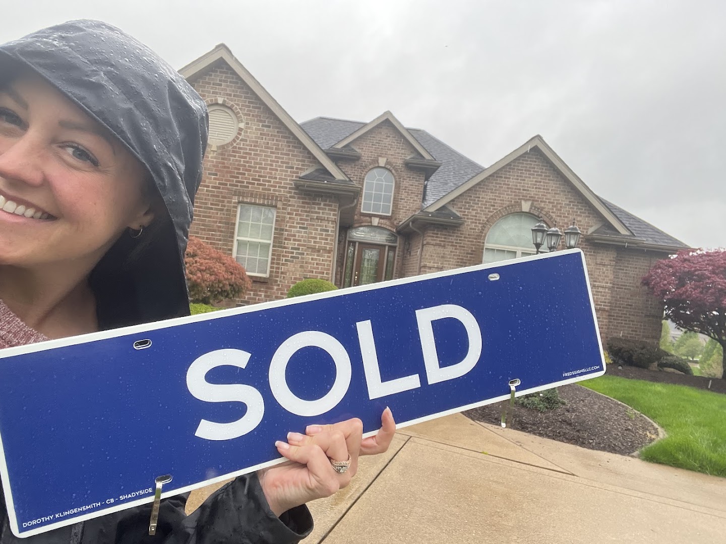 Realtor holding a SOLD sign outside a sold brick colonial home in the Pittsburgh area