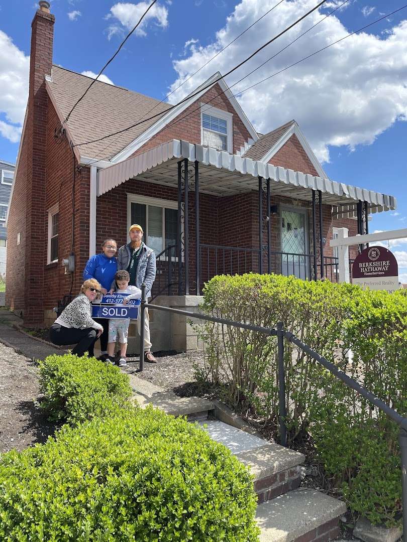 Family posing with SOLD sign in front of their new brick bungalow in Pittsburgh